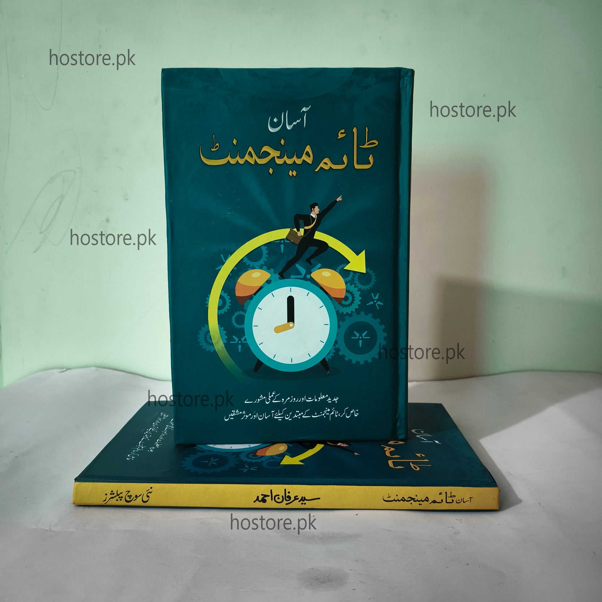 Book with a green cover featuring a clock and urdu text on a white surface.